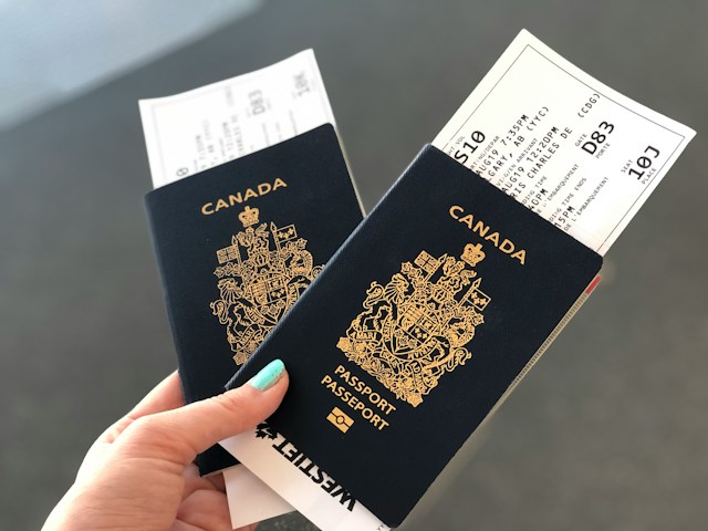 A woman holds two Canadian passports with boarding passes in them.
