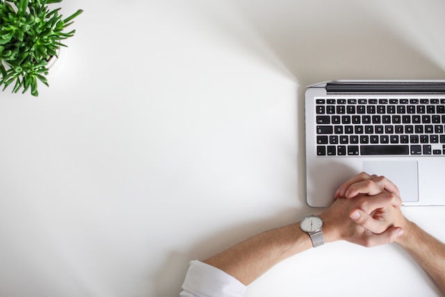 An overhead picture of a person watching their computer screen on a white table.