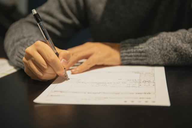 A person filling a form on a table.