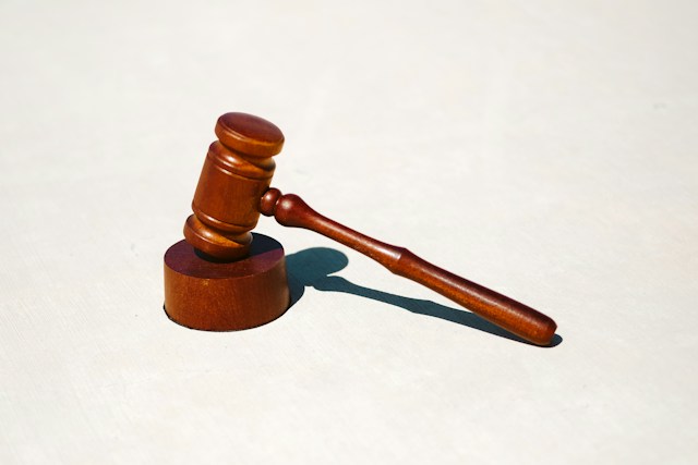 A brown gavel is on a round wooden block. 