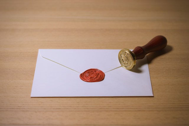 A photo of a white envelope with a brown stamp beside it.