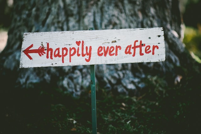 "Happily ever after” written red on a white signpost.
