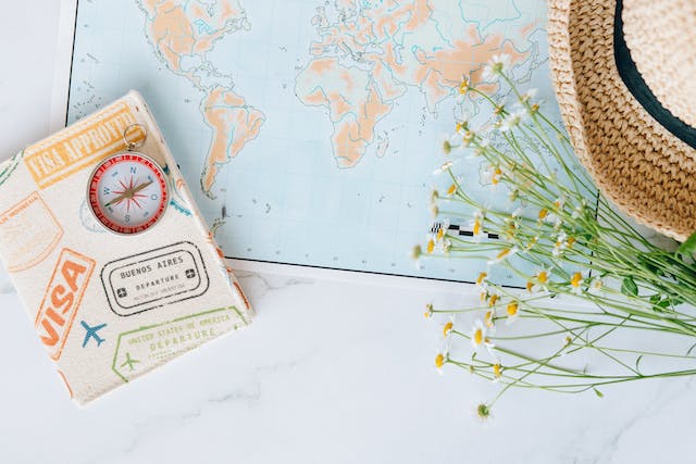A compass, an approved visa, and a flower placed on a map.
