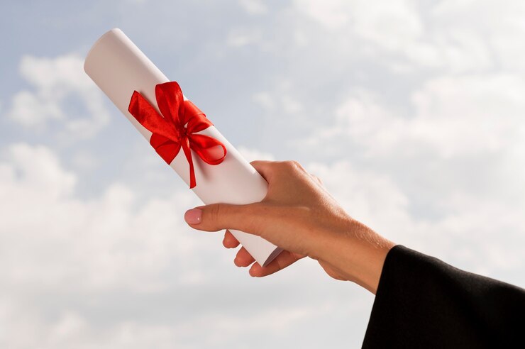 A person holds a certificate tied in a bow with a red ribbon.