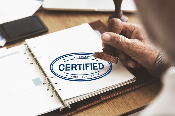 A person stamps the word “Certified” on a booklet page.