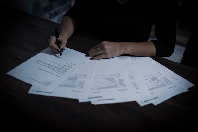 A person goes through a stack of documents on a table.