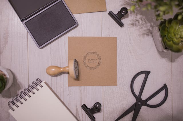 A brown wooden stamp on a piece of paper with other stationery on a table.
