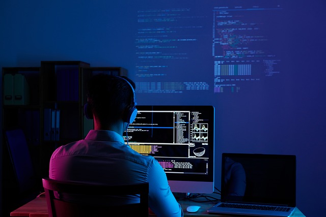 A person uses a black desktop computer in a dimly lit room.