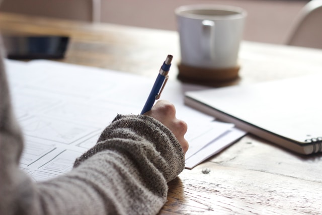 A lady studies for an exam with a cup of coffee on the table