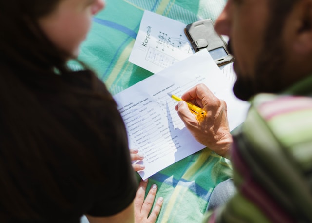 Two people fill out a document written in a foreign language.
