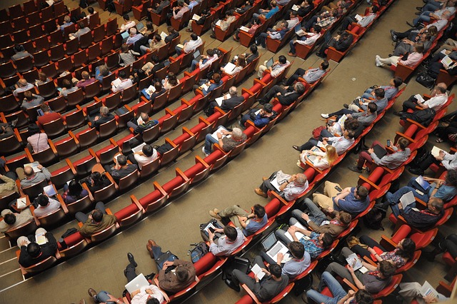 People sit in rows in an auditorium.
