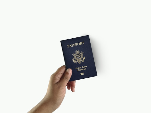 A hand holds the United States Passport booklet on a white background.
