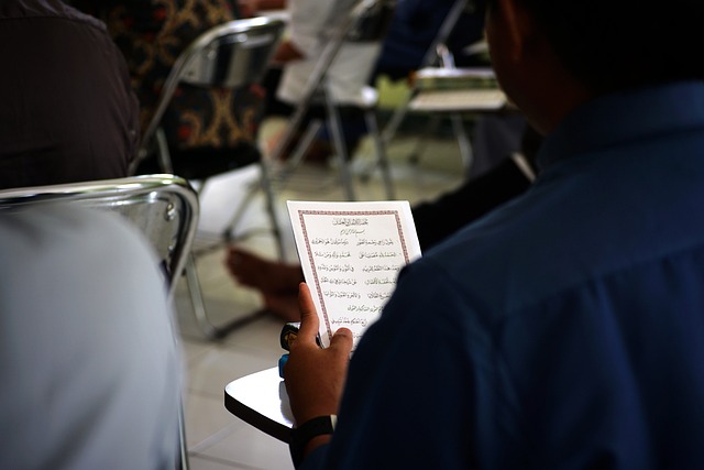 A person reads Arabic text on a piece of paper.