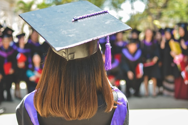 The back view of a person wearing a graduation gown and hat.
