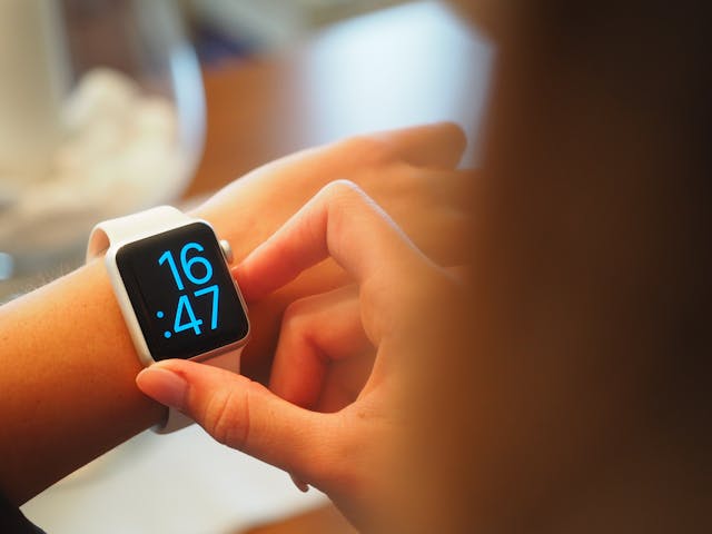 A person checks the time on a gray Apple watch.
