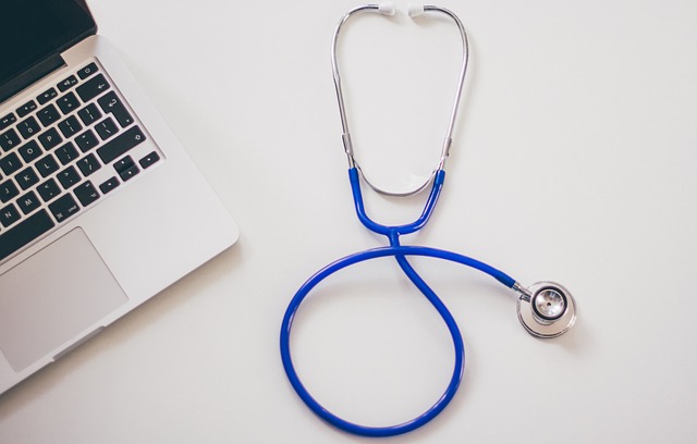 A stethoscope and silver laptop on a white surface.

