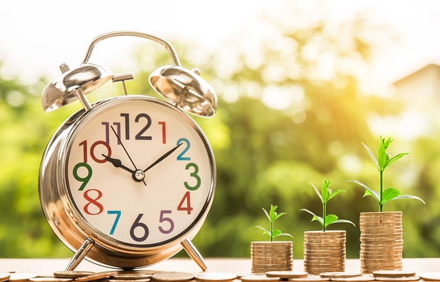 A clock beside three stacks of coins.
