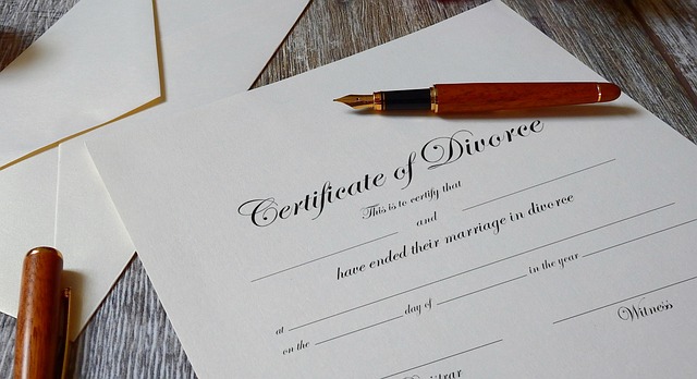 A pen is on an empty divorce certificate placed on a wooden surface.
