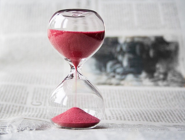 An hourglass containing pink sand is on a white surface.
