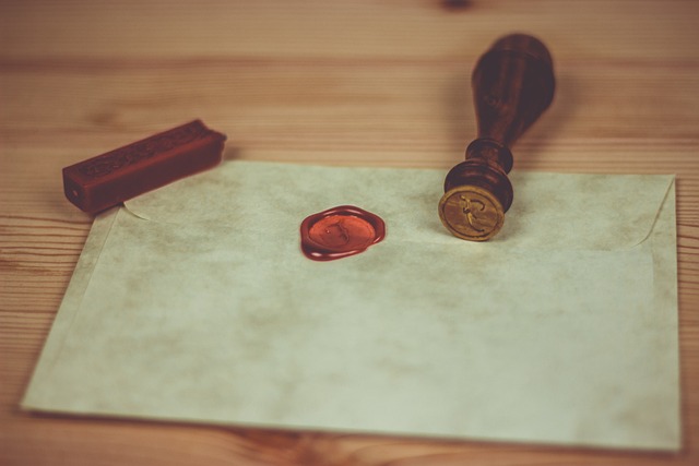 A stamp and red wax seal lie on a white envelope.