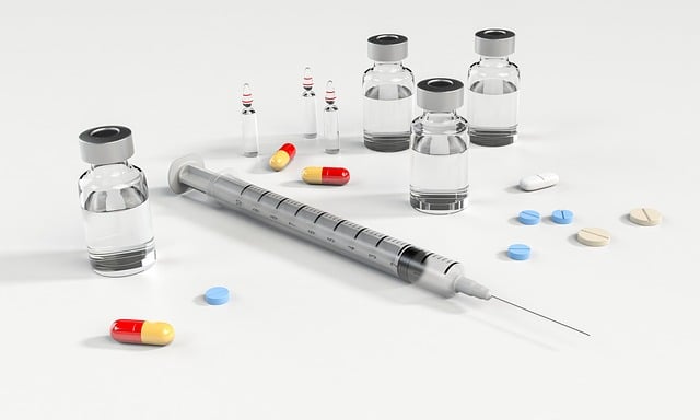 A syringe, drug vials, pills, and capsules on a white surface.
