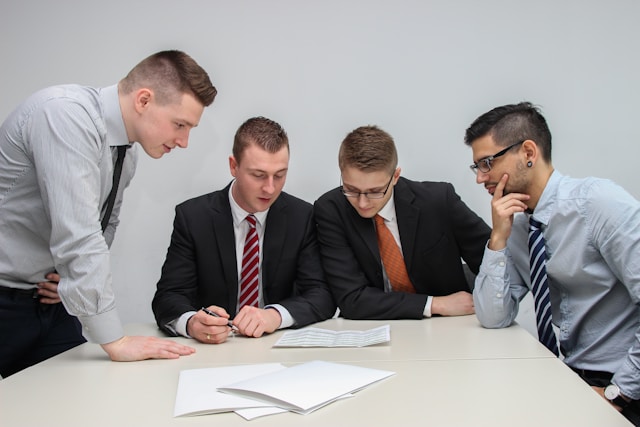 Employee Handbook Translation: How To Get This Service 5 Four people review a handbook on a table.