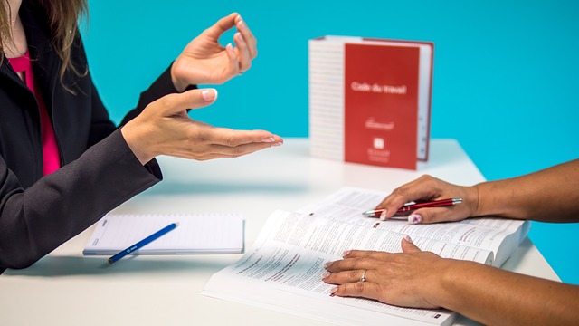 Employee Handbook Translation: How To Get This Service 4 Two people discuss over a table with the labor code handbook.