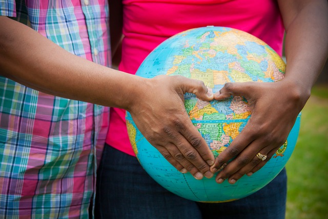 What Is the Easiest Country To Adopt From? 3 A close-up of two people forming a love heart with their hands over a globe.